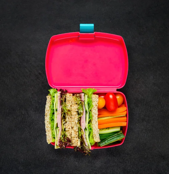 Pink Lunch Box with Vegetables and Sandwich