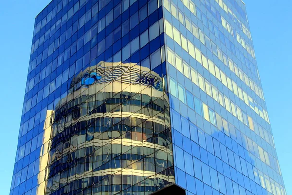 . runder Glasturm spiegelt sich im gläsernen Gebäude. — Stockfoto