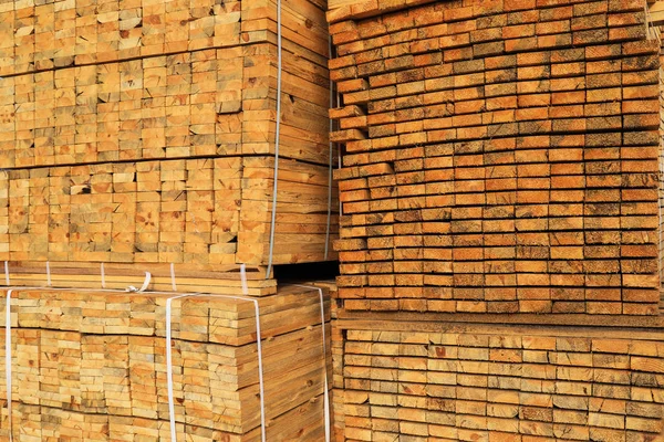 Wooden boards are piled in stacks at the yard of a construction supermarket. Industrial background, lumber, industrial wood. Pine wood timber for furniture production