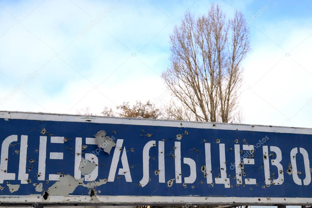 The war in Ukraine. A road sign with an inscription in Ukrainian - Debaltseve, shot down by bullets during the war. Armed conflict in Donetsk region, east of Ukraine, destruction