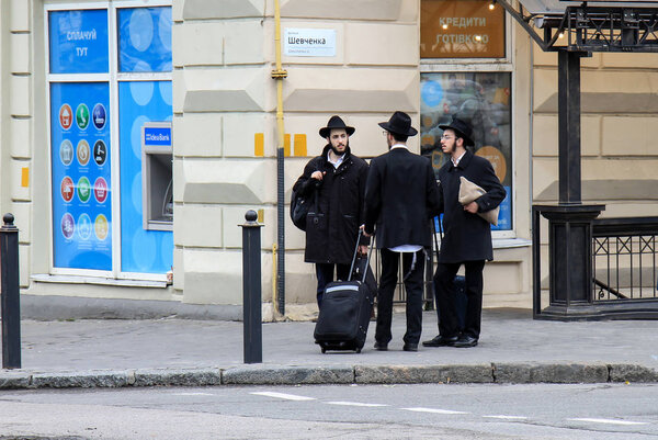 3 Jewish boys, Hasidic Jews, in black clothes and hats with suitcases and luggage stand on the street. Religious Orthodox Jew, Hasidim, Dnepropetrovsk city, Ukraine. 5 11 2018. 