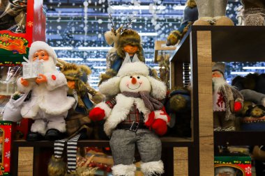 Güzel beyaz kardan adamlar ve kırmızı şapkalı bebekler. Mağazada en sevilen Noel oyuncakları ve yeni yıl oyuncakları. Bir alışveriş merkezinde Noel alışverişi..