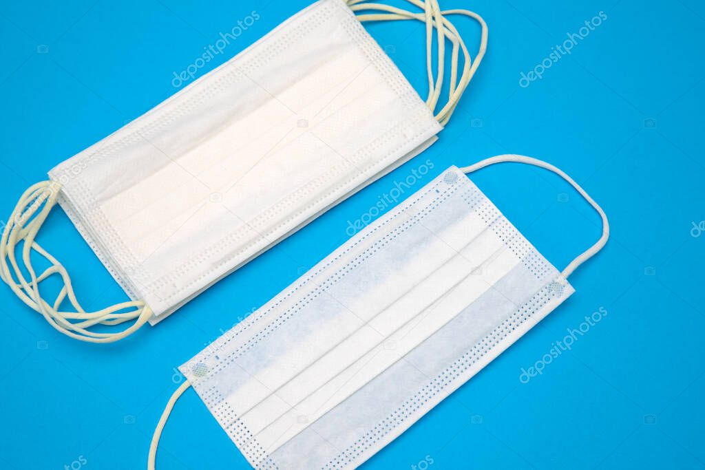 Protective medical disposable masks. White face masks, protection against viruses and bacteria, on a blue background, close-up, for quarantine during a coronavirus pandemic covid-19