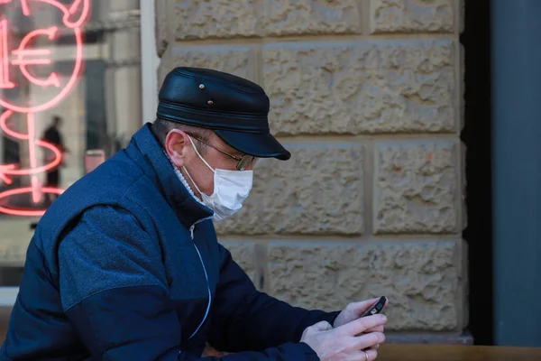 Uomo Maschera Medica Siede Sulla Strada Guarda Uno Smartphone Durante — Foto Stock