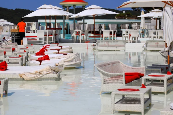 Beautiful picturesque summer view of the beach, umbrellas by the luxury pool. White fashionable sun loungers and chairs, beach furniture by the sea, Sibenik, Croatia 22 06 2019
