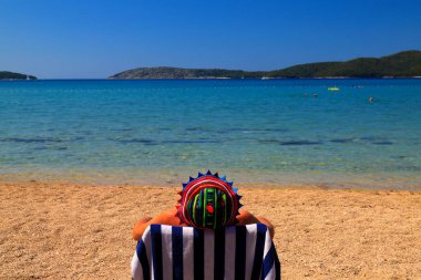 Hırvatistan 'da Blue Flag' in altında temiz bir ekolojik plajda güverte koltuğunda oturan komik panamalı bir adam. Deniz suyu, seyahat ve turizm yakınında yaz tatili