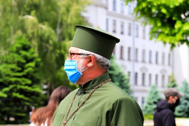 Dnipro, şehir, Ukrayna, 24 05 2020. Kilise kıyafetleri, cübbe ve tıbbi maske giymiş bir rahip cadde boyunca yürüyor. Coronavirüs salgını sırasında hastalığın önlenmesi Covid 19, karantina