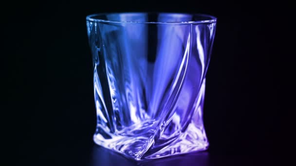 Whisky wird in ein Glas auf schwarzem Hintergrund gegossen — Stockvideo