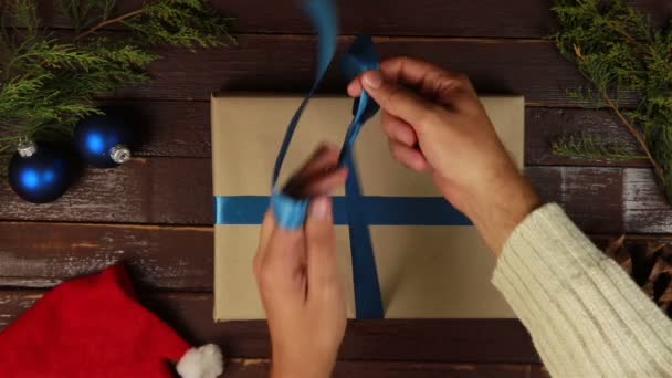 Hände verpacken Weihnachtsgeschenke von oben am Holztisch — Stockvideo