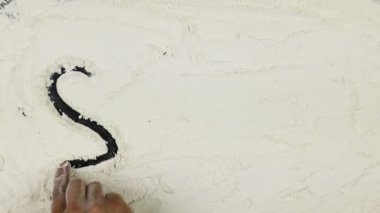 Genç adam bir kelime gülümseme beyaz un üzerinde yazıyor.