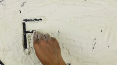 Genç adam bir kelime gıda üzerinde beyaz un yazıyor