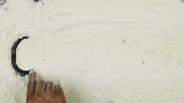 Молодий чоловік пише слово кекс на білому борошні — стокове відео