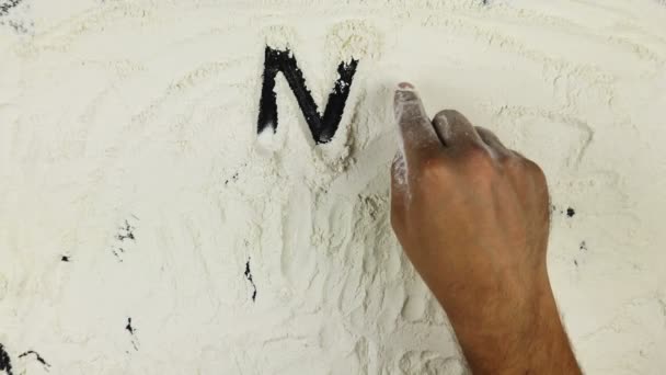 Young man writes a word no gluten on white flour — Stock Video