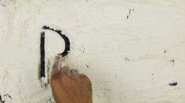 Genç adam bir kelime makarna beyaz un üzerinde yazıyor