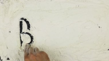 Genç adam bir kelime ekmek üzerinde beyaz un yazıyor.