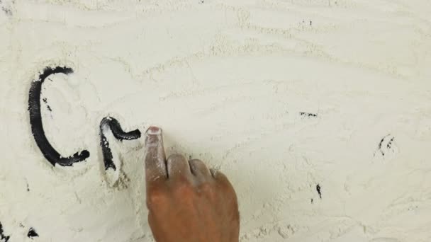 Young man writes a word croissant on white flour — Stock Video