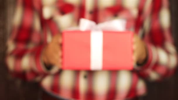 Ung man ger en gåva på trä bakgrund. Röd presentbox med vita band öppning. Gratulera gott nytt år, god jul, glad Alla hjärtans dag, presenterar gåvor — Stockvideo