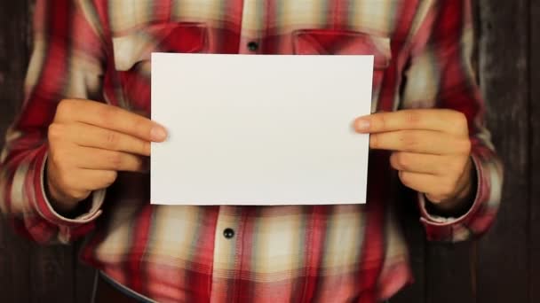 Giovane uomo Presentando un foglio bianco con felice anno nuovo su sfondo di legno — Video Stock
