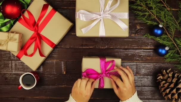 Felülnézet kezek kicsomagolási karácsonyi ajándékokat, fából készült íróasztal, felülről — Stock videók