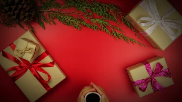 Draufsicht Hände trinken Kaffee Weihnachtsgeschenke Tisch auf rotem Hintergrund von oben. — Stockvideo