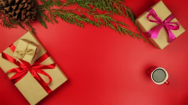 Το Top view χέρια κρατώντας χριστουγεννιάτικα δώρα σε κόκκινο φόντο από πάνω. Δώρο τυλιγμένο σε καφέ χαρτί και δεμένα λευκή κορδέλα — Αρχείο Βίντεο
