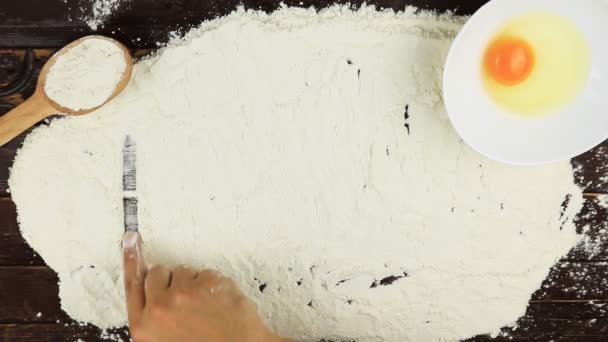 Top view Young man writes a word bake on white flour at wooden desk from above. — Stock Video