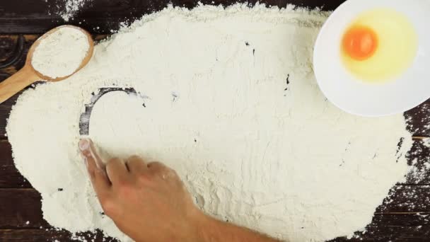 Vue de dessus Jeune homme écrit un gâteau mot sur la farine blanche au bureau en bois d'en haut . — Video