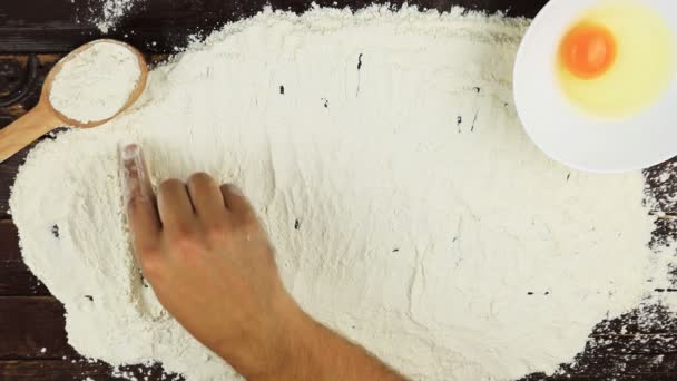 Top view Young man writes a word pastry on white flour at wooden desk from above. — Stock Video