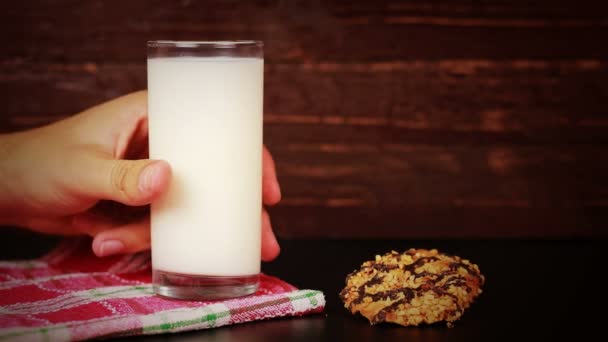 Młodego człowieka, picie mleka i cookie na podłoże drewniane — Wideo stockowe