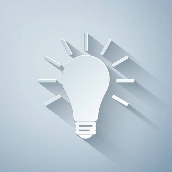 Pappersklipp Glödlampa med strålar lysa ikon isolerad på grå bakgrund. Energi och idé symbol. Lampan är elektrisk. Papperskonst. Vektor Illustration — Stock vektor