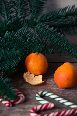 Ahşap masa üzerinde mandalina ve şeker kamışı. Noel ruh hali.