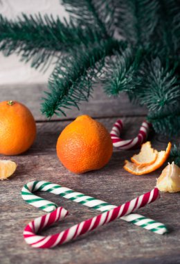 Ahşap masa üzerinde mandalina ve şeker kamışı. Noel ruh hali.