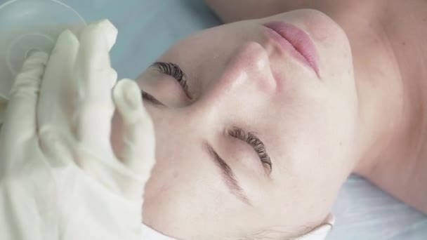 El cosmetólogo aplica una máscara en la cara — Vídeos de Stock