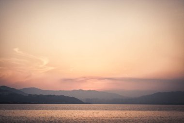 Deniz ve uzak dağ günbatımı