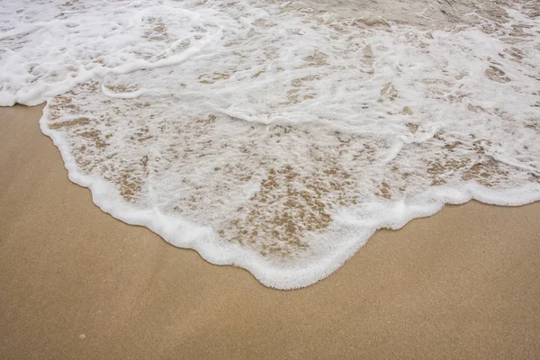Vague mousseuse sur une plage — Photo