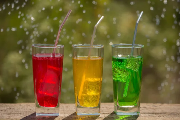 Three glasses of soda water on an old board, on the nature