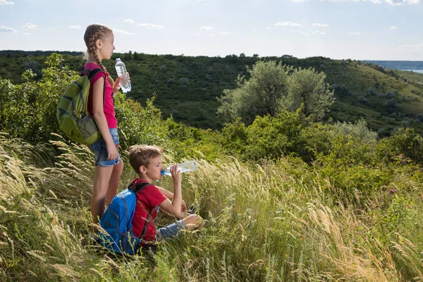 Kız duruyor ve oğlan bir uzun otların ve içme suyu, dinlenme ile bir açıklıkta oturuyor