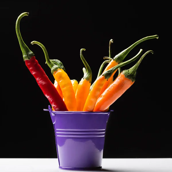 Yellow and red chili peppers in a colored bucket — Stock Photo, Image