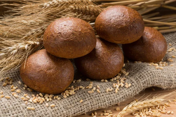 Five buns lined up in a sackcloth, in the background wheat ears — Stock Photo, Image