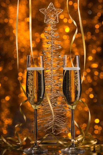 Två glas champagne med en gyllene bokeh bakgrund, festlig dekoration, jul leksaker — Stockfoto
