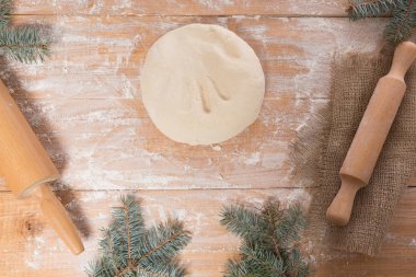 ahşap bir masa, oklava, bir tabloda bir Noel ağacının dalları üzerinde hamur