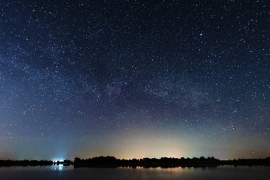 Nehir kıyısında, gökyüzünde büyük bir ağaç ve samanyolu ve yazın düşen yıldızlarla büyülü bir yıldızlı gece..