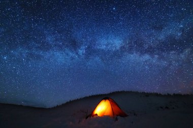 Çadırları olan turistlerin arka planında parlak Samanyolu ile uzay yıldızlı geceler.