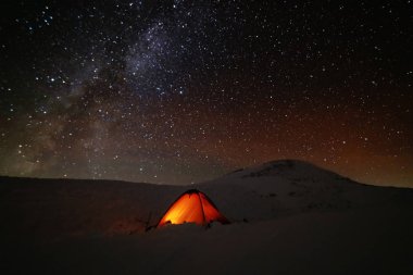 Çadırları olan turistlerin arka planında parlak Samanyolu ile uzay yıldızlı geceler.