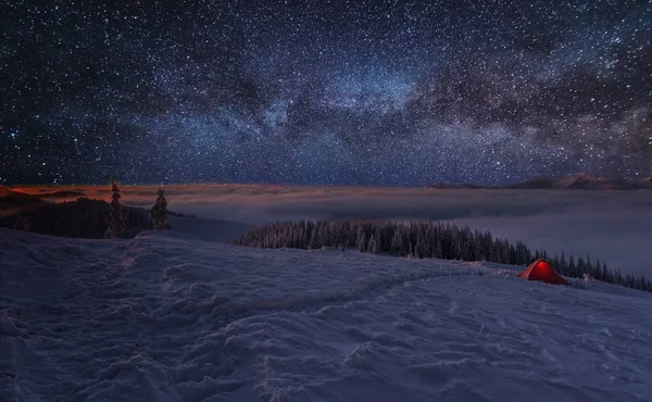 Çadırları olan turistlerin arka planında parlak Samanyolu ile uzay yıldızlı geceler.