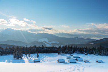 Karpatlar 'da bir dağ vadisinde karla kaplı büyüleyici evler, kışın muhteşem zirveler..