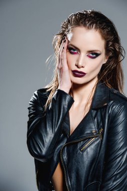 Stüdyoda poz veren deri ceketli şık bir genç kadın.