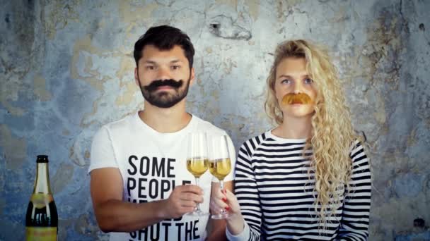 Crazy couple with fake mustache clinking champagne glasses, drinking and kissing. — Stock Video