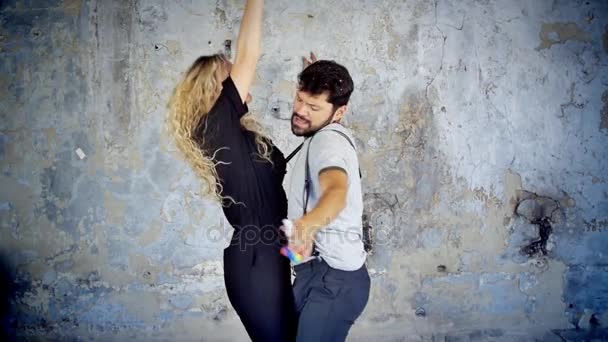 Gelukkige jonge paar in zonnebrillen en hoeden dansen in slow-motion luisteren naar muziek met plezier in de liefde. — Stockvideo