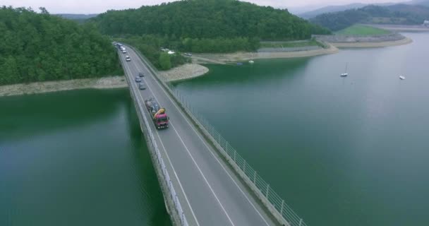 Gesamtansicht der großen Brücke über das Meer, am hinteren Seeufer, dichter Wald und Segelboote Luftaufnahme — Stockvideo